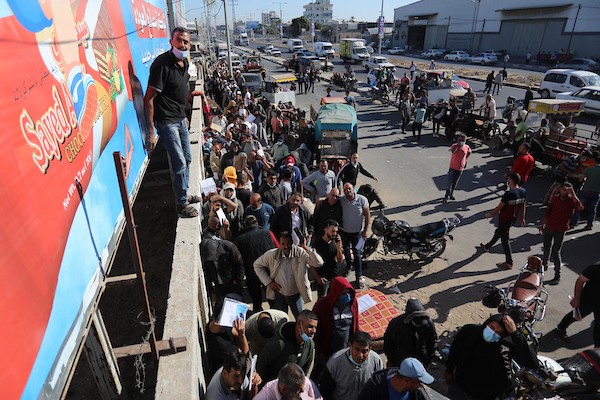 مواطنون فلسطينيون ينتظرون أمام مقر الغرفة التجارية للتسجيل من اجل العمل في إسرائيل، في دير البلح وسط قطاع غزة(30)