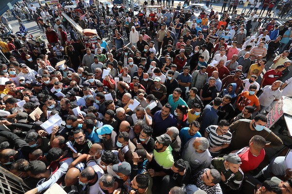 مواطنون فلسطينيون ينتظرون أمام مقر الغرفة التجارية للتسجيل من اجل العمل في إسرائيل، في دير البلح وسط قطاع غزة