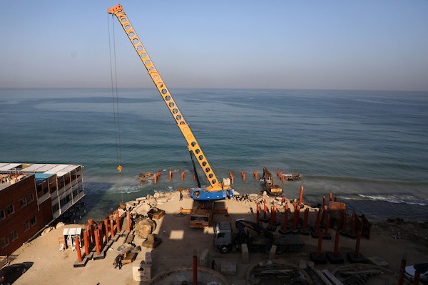 عمال فلسطينيون يديرون جرافة لنصب ركائز في البحر الأبيض المتوسط ​​لبناء مقهى القلعة وهو أول مقهى خرساني عائم على شاطئ مدينة غزة باستخدام مواد بسيطة 24