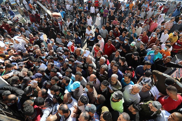 مواطنون فلسطينيون ينتظرون أمام مقر الغرفة التجارية للتسجيل من اجل العمل في إسرائيل، في دير البلح وسط قطاع غزة