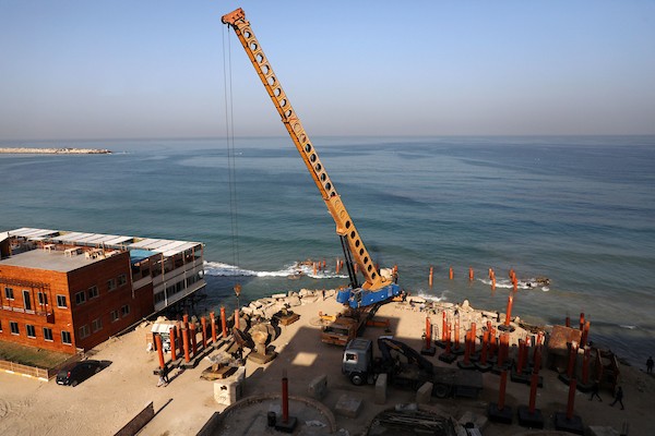 عمال فلسطينيون يديرون جرافة لنصب ركائز في البحر الأبيض المتوسط ​​لبناء مقهى القلعة وهو أول مقهى خرساني عائم على شاطئ مدينة غزة باستخدام مواد بسيطة 12