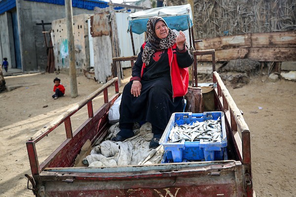 المسنة الفلسطينية أم جميل الأقرع من دير البلح وسط قطاع غزة تشتري الأسماك من الحسبة لتبيعها في السوق، لتعيل أسرتهامع احتفال العالم بيوم المرأة العالمي.