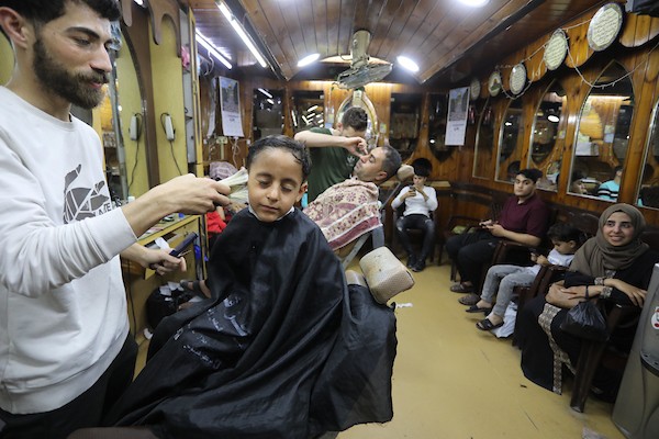الفلسطينيون يقصون شعورهم داخل محل لتصفيف الشعر في مدينة خانيونس استعدادا لعيد الفطر 9.jpg