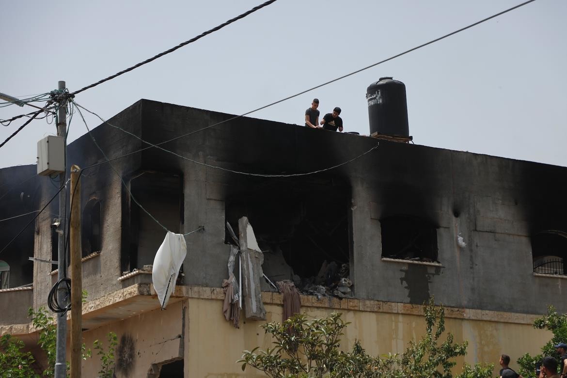 مواطنون يتفقدون بناية سكنية في مخيم جنين قصفتها قوات الاحتلال بالقذائف، بعد محاصرتها منذ ساعات الصباح