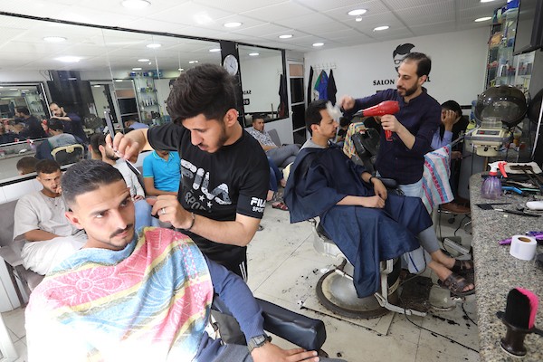 الفلسطينيون يقصون شعورهم داخل محل لتصفيف الشعر في مدينة خانيونس استعدادا لعيد الفطر 1.jpg