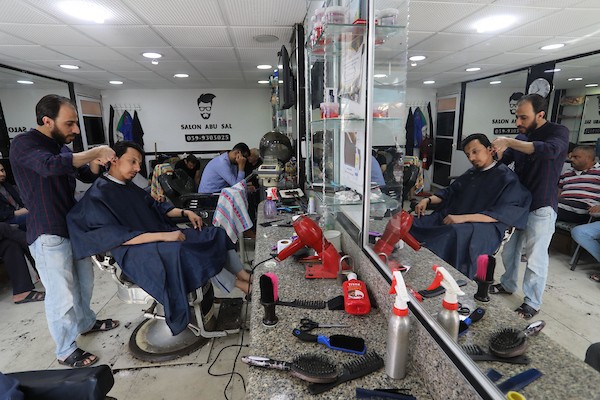 الفلسطينيون يقصون شعورهم داخل محل لتصفيف الشعر في مدينة خانيونس استعدادا لعيد الفطر.jpg