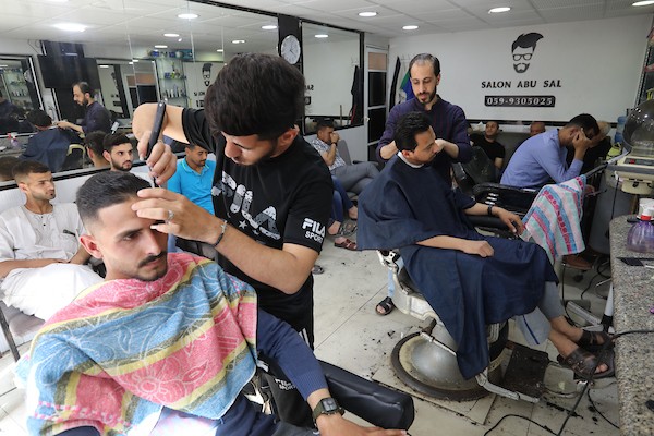 الفلسطينيون يقصون شعورهم داخل محل لتصفيف الشعر في مدينة خانيونس استعدادا لعيد الفطر 3.jpg