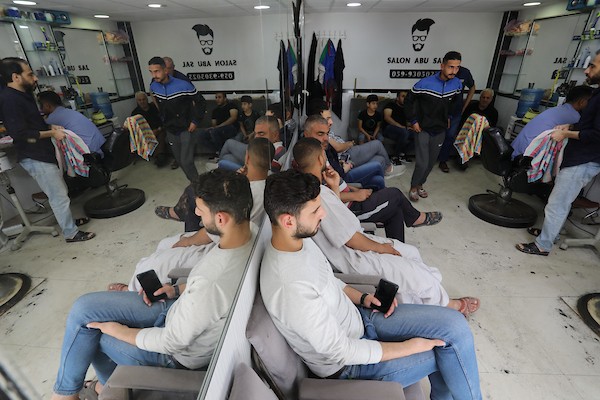 الفلسطينيون يقصون شعورهم داخل محل لتصفيف الشعر في مدينة خانيونس استعدادا لعيد الفطر 6.jpg