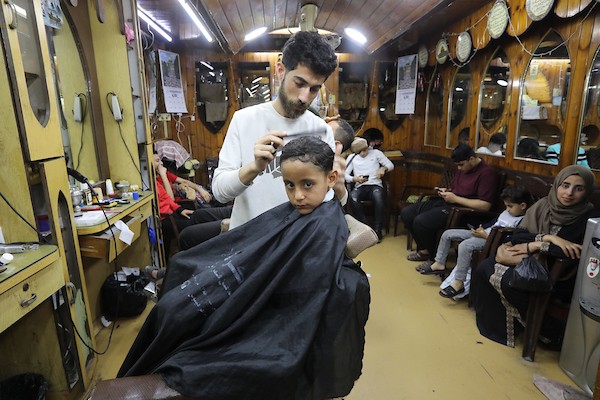 الفلسطينيون يقصون شعورهم داخل محل لتصفيف الشعر في مدينة خانيونس استعدادا لعيد الفطر 7.jpg