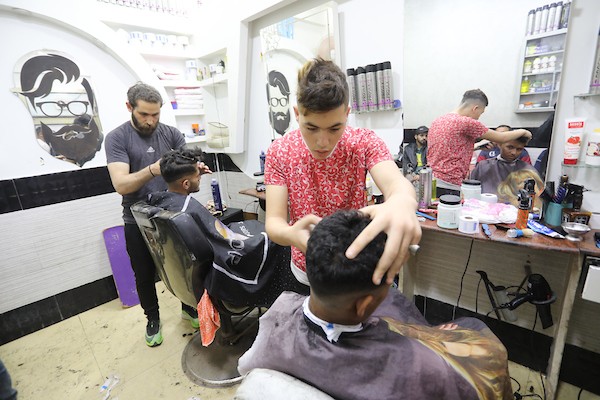 الفلسطينيون يقصون شعورهم داخل محل لتصفيف الشعر في مدينة خانيونس استعدادا لعيد الفطر 11.jpg