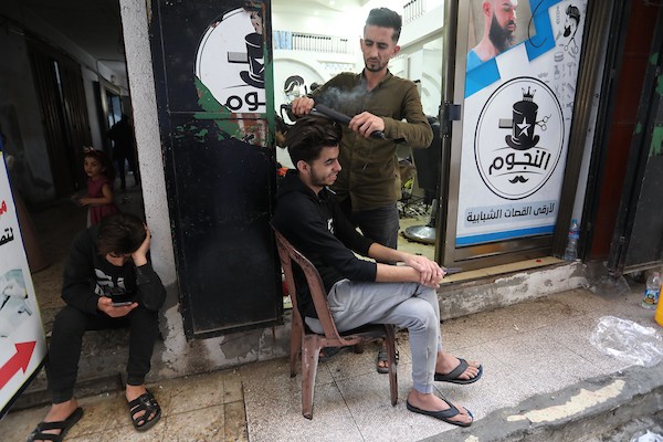 الفلسطينيون يقصون شعورهم داخل محل لتصفيف الشعر في مدينة خانيونس استعدادا لعيد الفطر2.jpg
