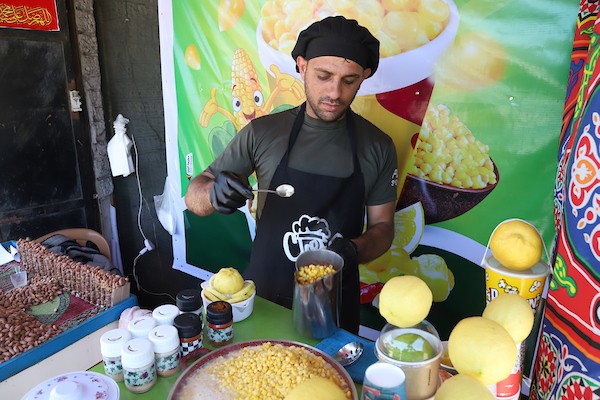 صلاح الخولي يتفنن في ابتكار طرق جديدة لبيع الذرة داخل كشك صغير وسط مدينة غزة.jpg