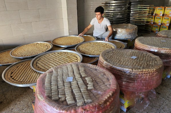 فلسطينيون يجهزون الحلويات داخل أحد المصانع استعدادا لنتائج الثانوية العامة في مدينة خانيونس 4.jpg