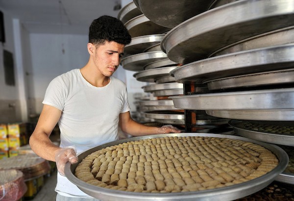 فلسطينيون يجهزون الحلويات داخل أحد المصانع استعدادا لنتائج الثانوية العامة في مدينة خانيونس.jpg