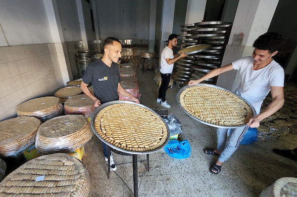 فلسطينيون يجهزون الحلويات داخل أحد المصانع استعدادا لنتائج الثانوية العامة في مدينة خانيونس 12.jpg