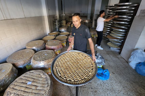 فلسطينيون يجهزون الحلويات داخل أحد المصانع استعدادا لنتائج الثانوية العامة في مدينة خانيونس 15.jpg