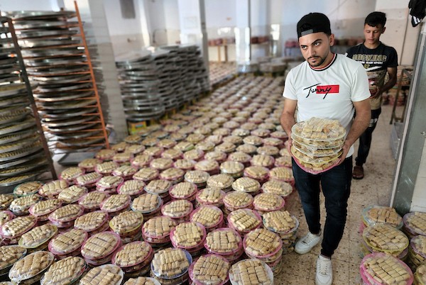 فلسطينيون يجهزون الحلويات داخل أحد المصانع استعدادا لنتائج الثانوية العامة في مدينة خانيونس 1.jpg