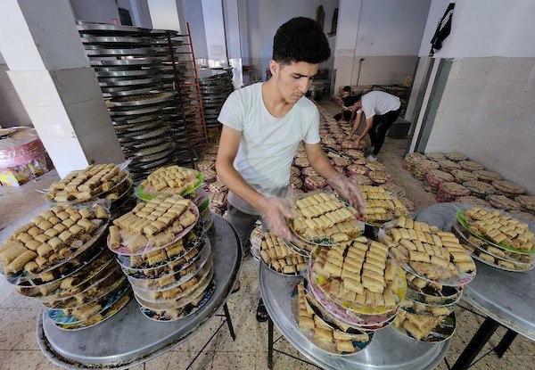 فلسطينيون يجهزون الحلويات داخل أحد المصانع استعدادا لنتائج الثانوية العامة في مدينة خانيونس 10.jpg