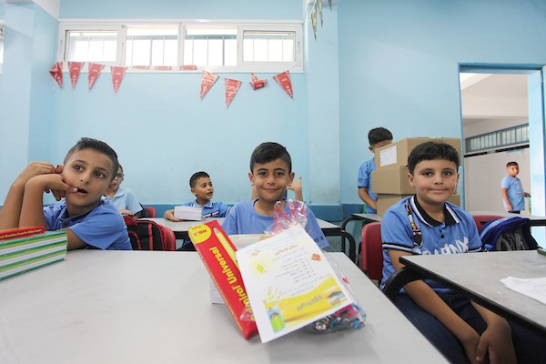طلاب فلسطينيون يستلمون القرطاسية المدرسي في اليوم الأول من العام الدراسي الجديد في مدرسة تابعة لوكالة الغوث في مدينة غزة 18.jpg