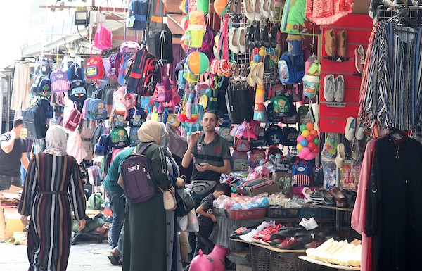 فلسطينيون يتسوقون استعداداً لاستقبال العام الدراسي الجديد في مخيم جباليا شمال قطاع غزة.jpg