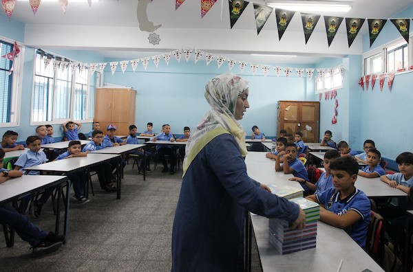طلاب فلسطينيون يستلمون القرطاسية المدرسي في اليوم الأول من العام الدراسي الجديد في مدرسة تابعة لوكالة الغوث في مدينة غزة 11.jpg
