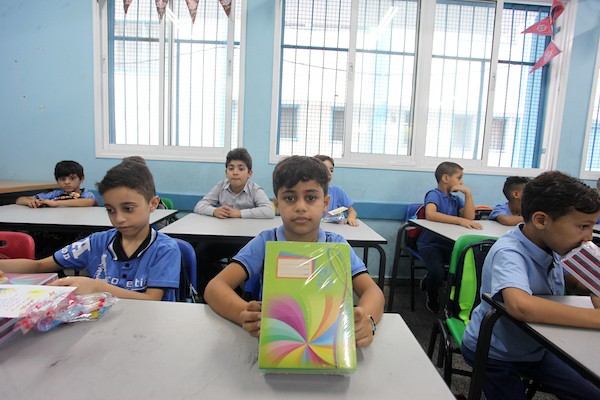 طلاب فلسطينيون يستلمون القرطاسية المدرسي في اليوم الأول من العام الدراسي الجديد في مدرسة تابعة لوكالة الغوث في مدينة غزة 16.jpg