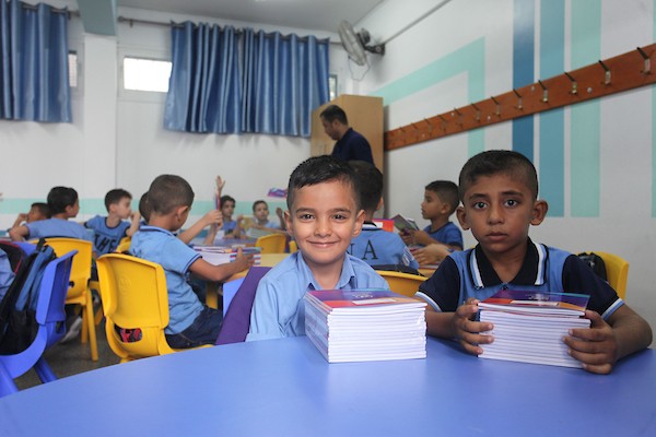 طلاب فلسطينيون يستلمون القرطاسية المدرسي في اليوم الأول من العام الدراسي الجديد في مدرسة تابعة لوكالة الغوث في مدينة غزة 4.jpg