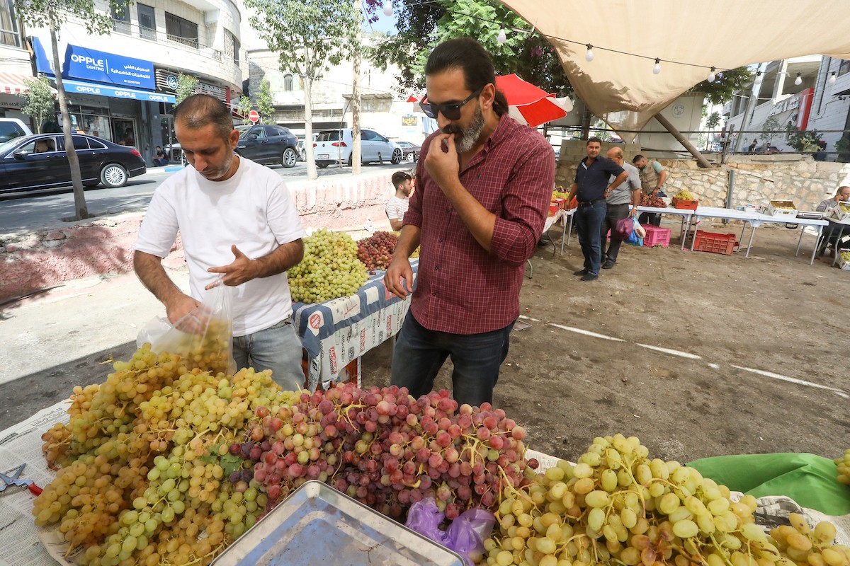 بائعون فلسطينيون يبيعون العنب في سوق للعنب في مدينة رام الله بالضفة الغربية.jpg