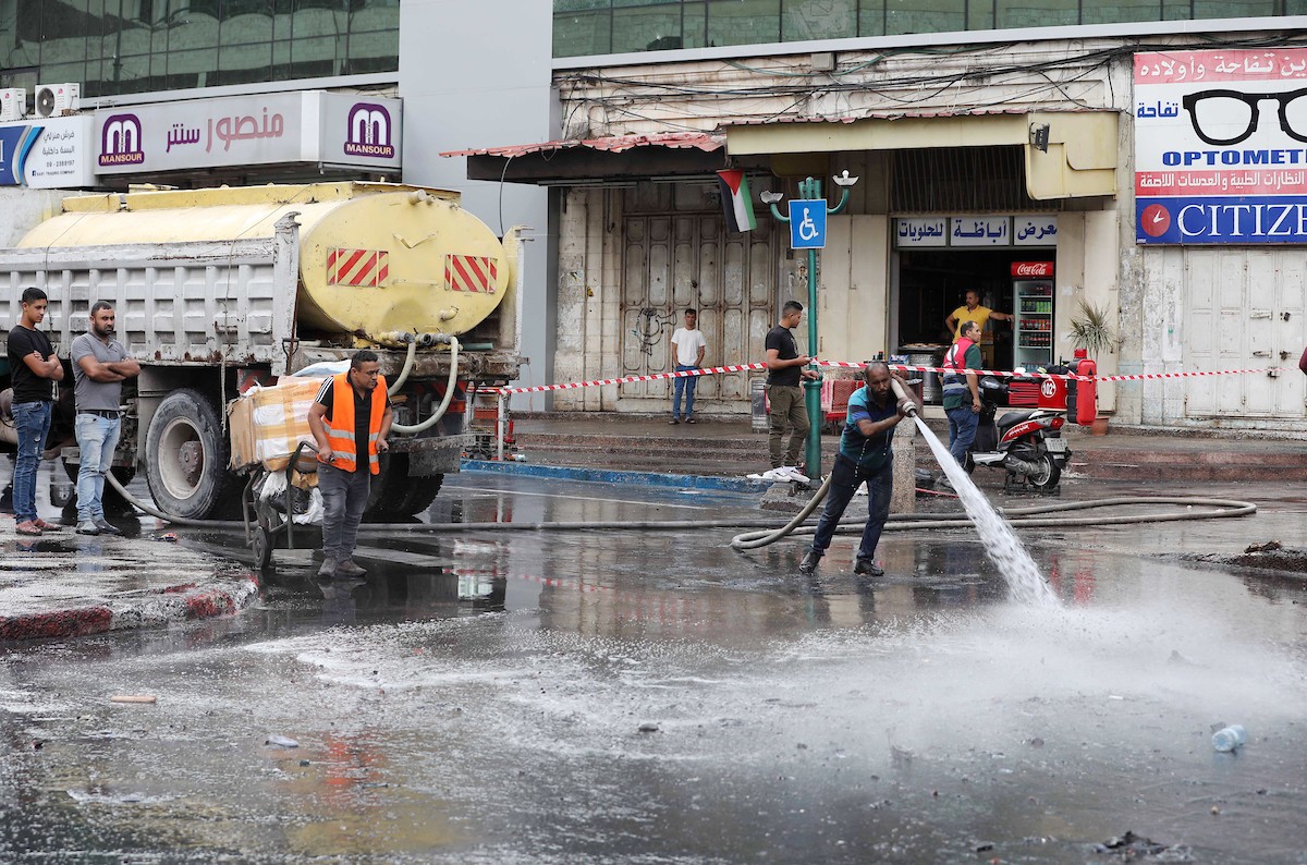 فلسطينيون ينظفون الشوارع بعد عودة الهدوء إلى مدينة نابلس بالضفة الغربية 9.jpg