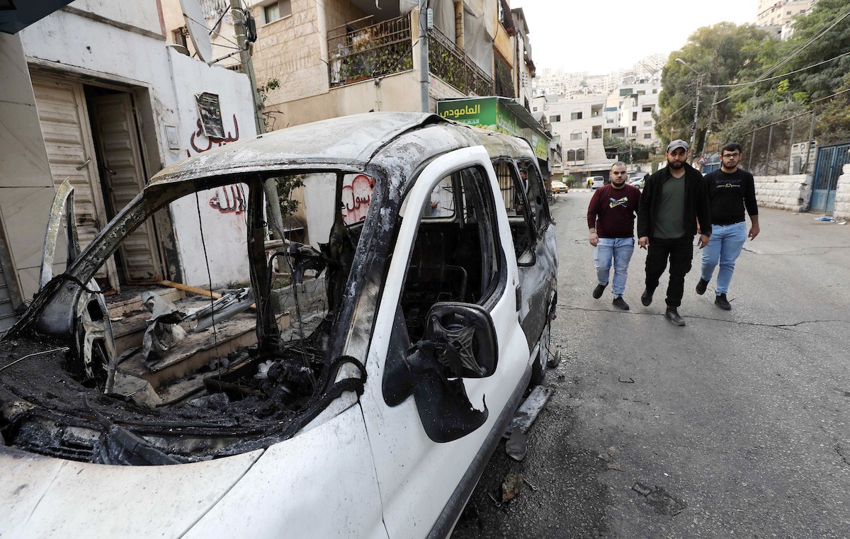 فلسطينيون يتجمعون حول سيارة محترقة بعد اقتحام جيش الاحتلال لمدينة نابلس 3.jpg