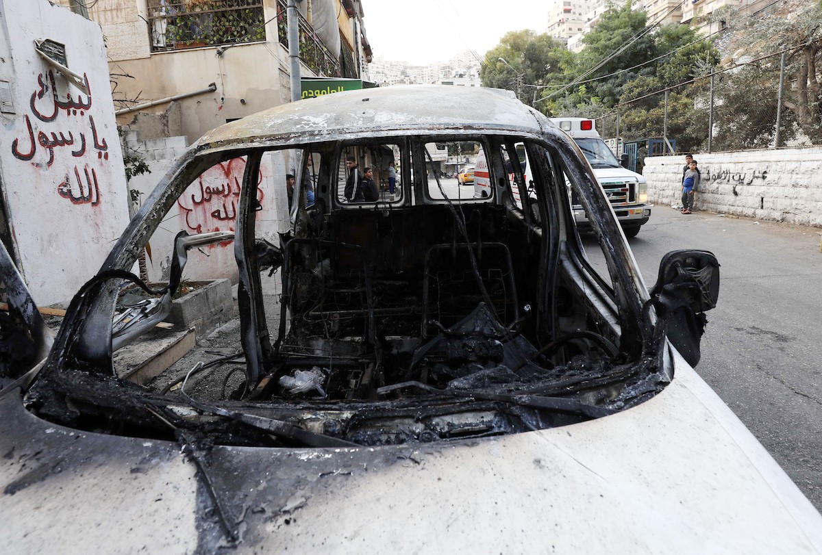 فلسطينيون يتجمعون حول سيارة محترقة بعد اقتحام جيش الاحتلال لمدينة نابلس.jpg