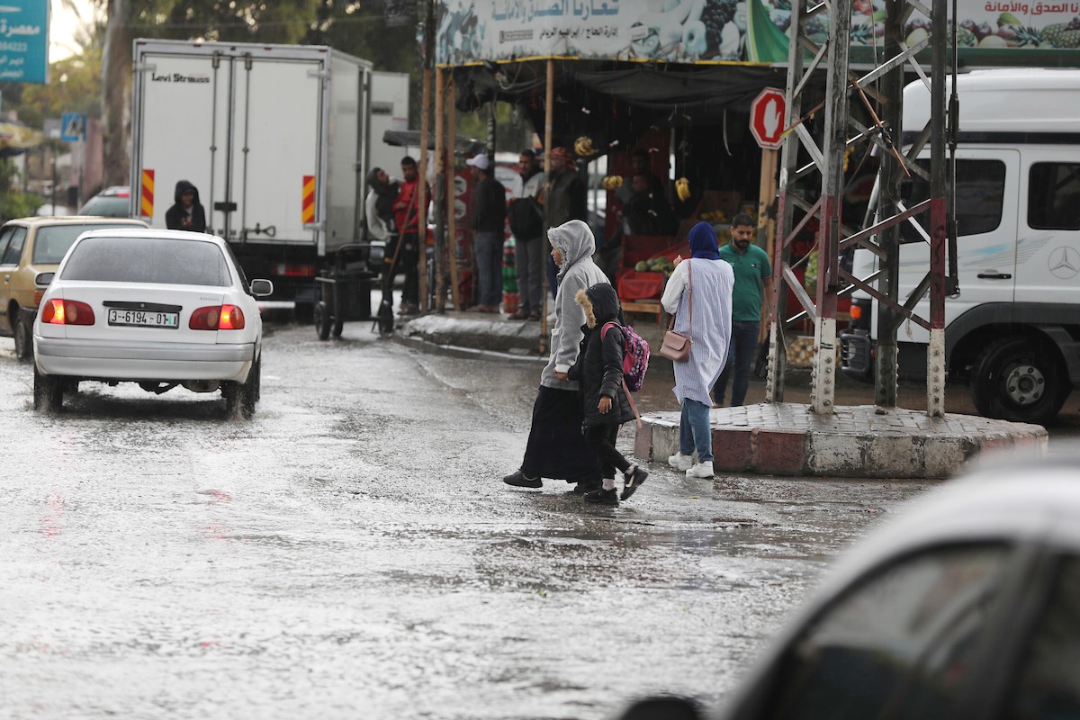 فلسطينيون يسيرون في شارع غمرته مياه الأمطار في دير البلح وسط قطاع غزة 8.jpg