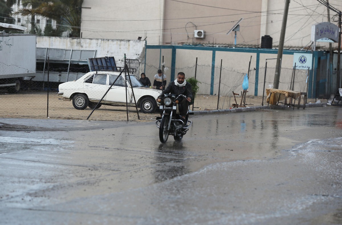 فلسطينيون يسيرون في شارع غمرته مياه الأمطار في دير البلح وسط قطاع غزة 76.jpg