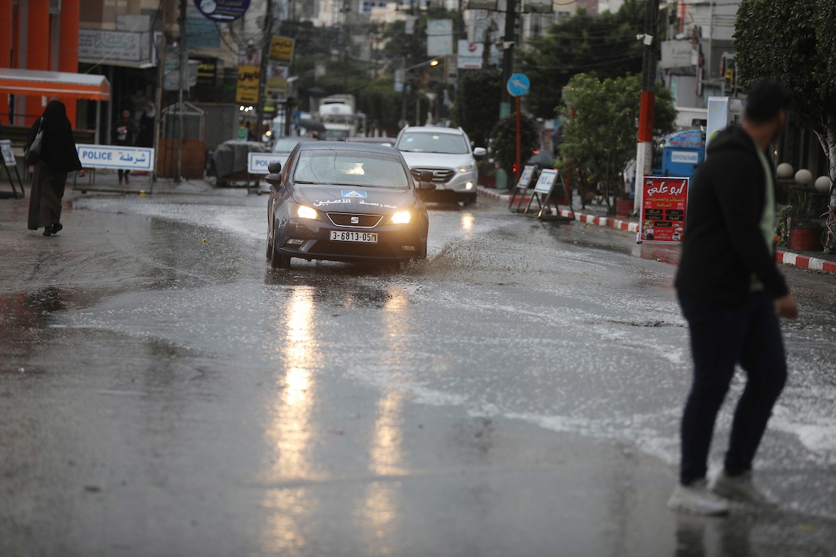 فلسطينيون يسيرون في شارع غمرته مياه الأمطار في دير البلح وسط قطاع غزة 3.jpg
