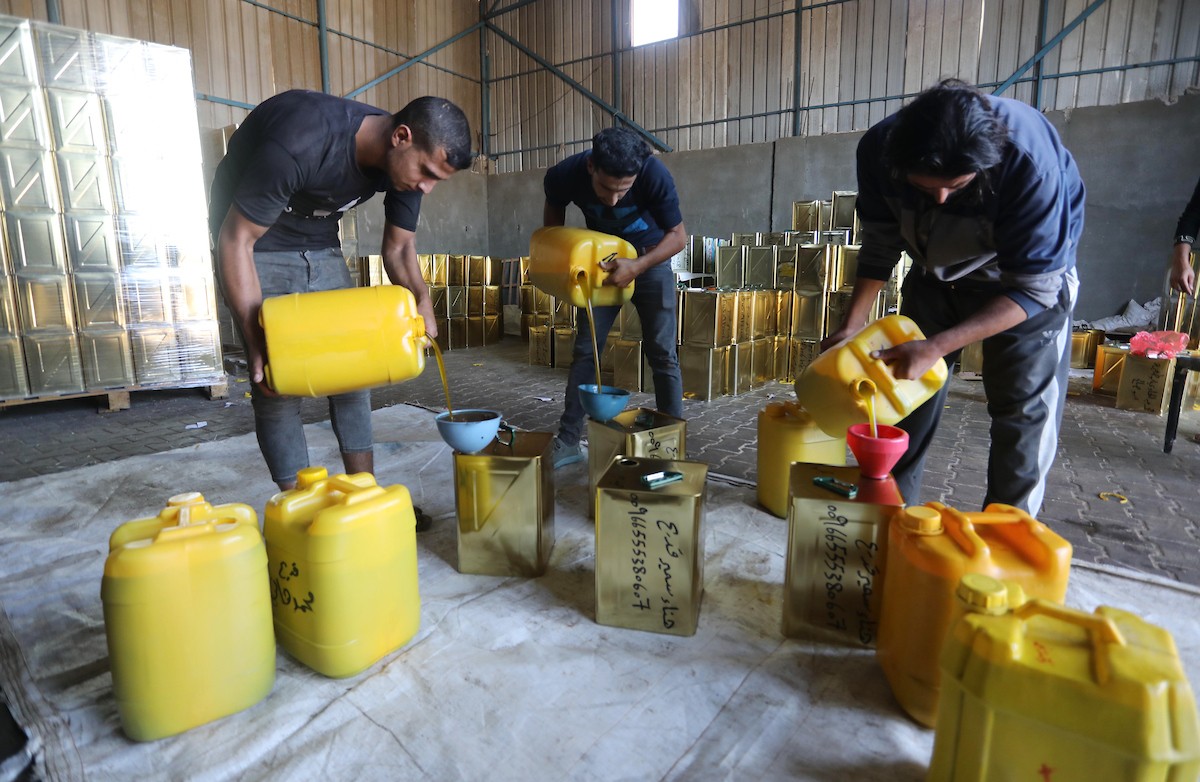 عمال فلسطينيون يجهزون صفائح زيت الزيتون لتصديرها لدول الخليج في مدينة خان يونس جنوب قطاع غزة 2.jpg