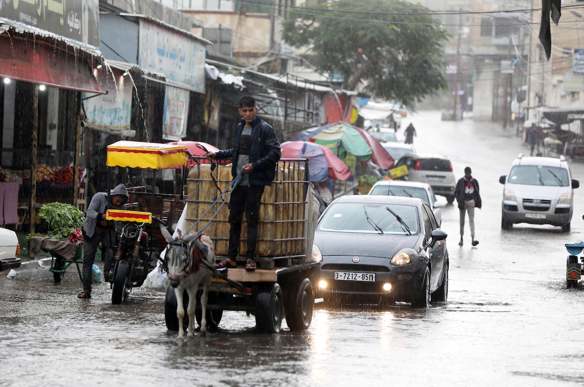 فلسطينيون يسيرون في شارع غمرته مياه الأمطار في دير البلح وسط قطاع غزة 54(1).jpg