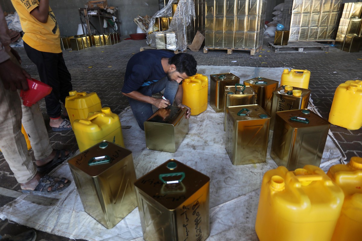 عمال فلسطينيون يجهزون صفائح زيت الزيتون لتصديرها لدول الخليج في مدينة خان يونس جنوب قطاع غزة 0.jpg