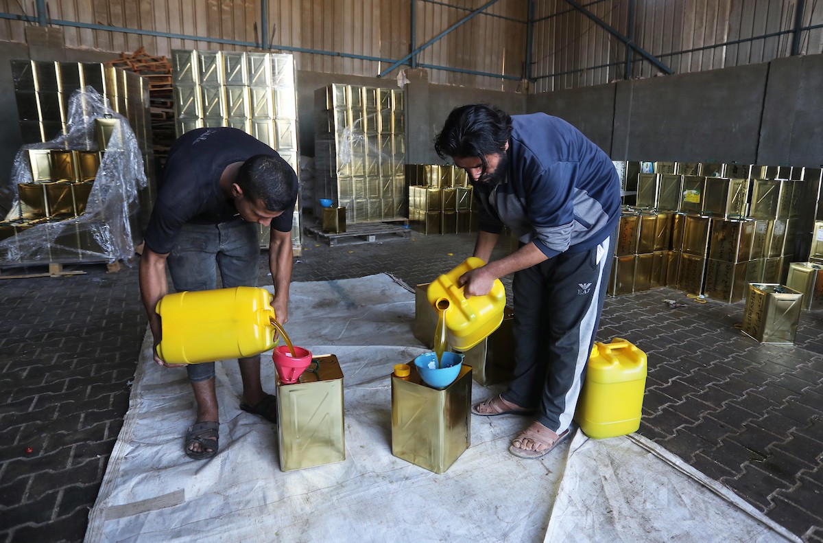 عمال فلسطينيون يجهزون صفائح زيت الزيتون لتصديرها لدول الخليج في مدينة خان يونس جنوب قطاع غزة 12.jpg