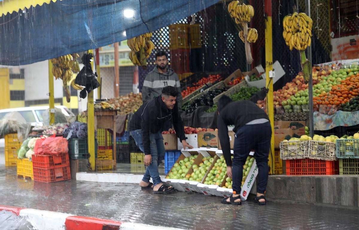 فلسطينيون يسيرون في شارع غمرته مياه الأمطار في دير البلح وسط قطاع غزة 11.jpg