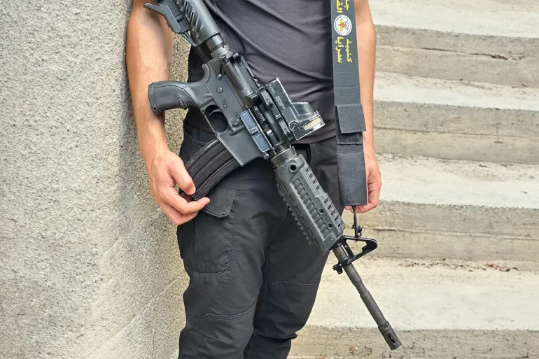 مقاتل من وحدة الاشتباك بكتيبة جنين يحمل سلاحه بعد يوم من اجتياح عنيف شهده المخيم (الجزيرة نت).webp