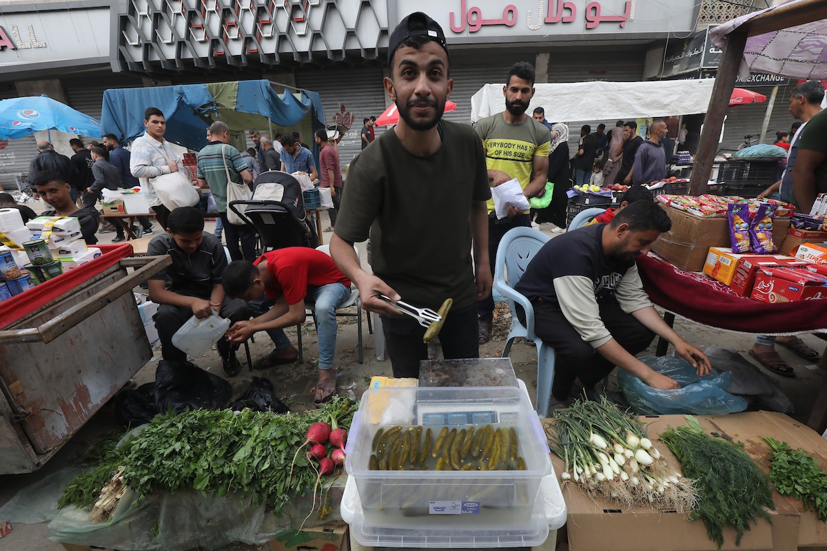 أشخاص يتسوقون من الباعة في سوق مفتوح وسط الدمار في النصيرات وسط قطاع غزة، 05 أبريل 2024. تصوير :نعمان عمر