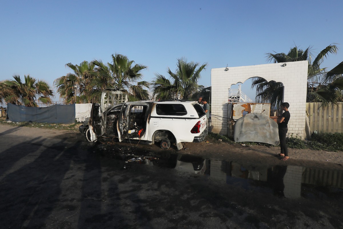 فلسطينيون يتفقدون المركبات المتضررة بشدة بعد الهجمات الإسرائيلية التي استهدفت المسؤولين العاملين في منظمة المساعدة التطوعية الدولية 