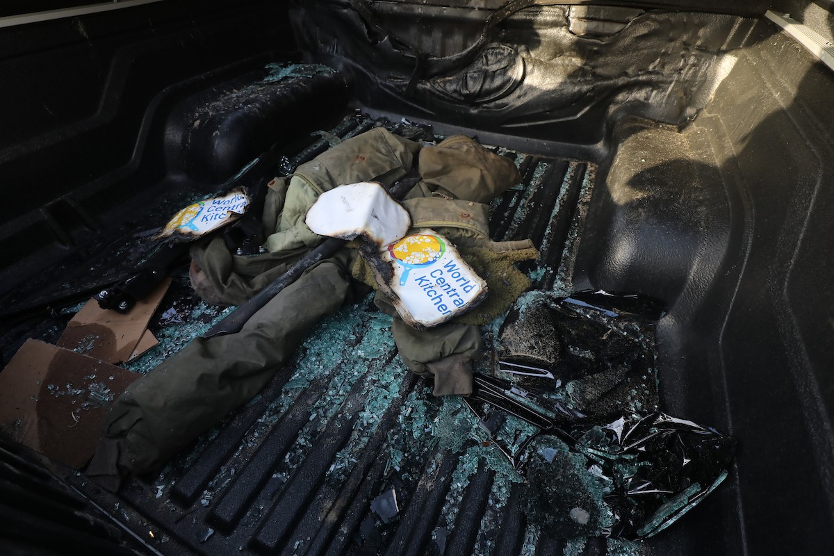فلسطينيون يتفقدون المركبات المتضررة بشدة بعد الهجمات الإسرائيلية التي استهدفت المسؤولين العاملين في منظمة المساعدة التطوعية الدولية 