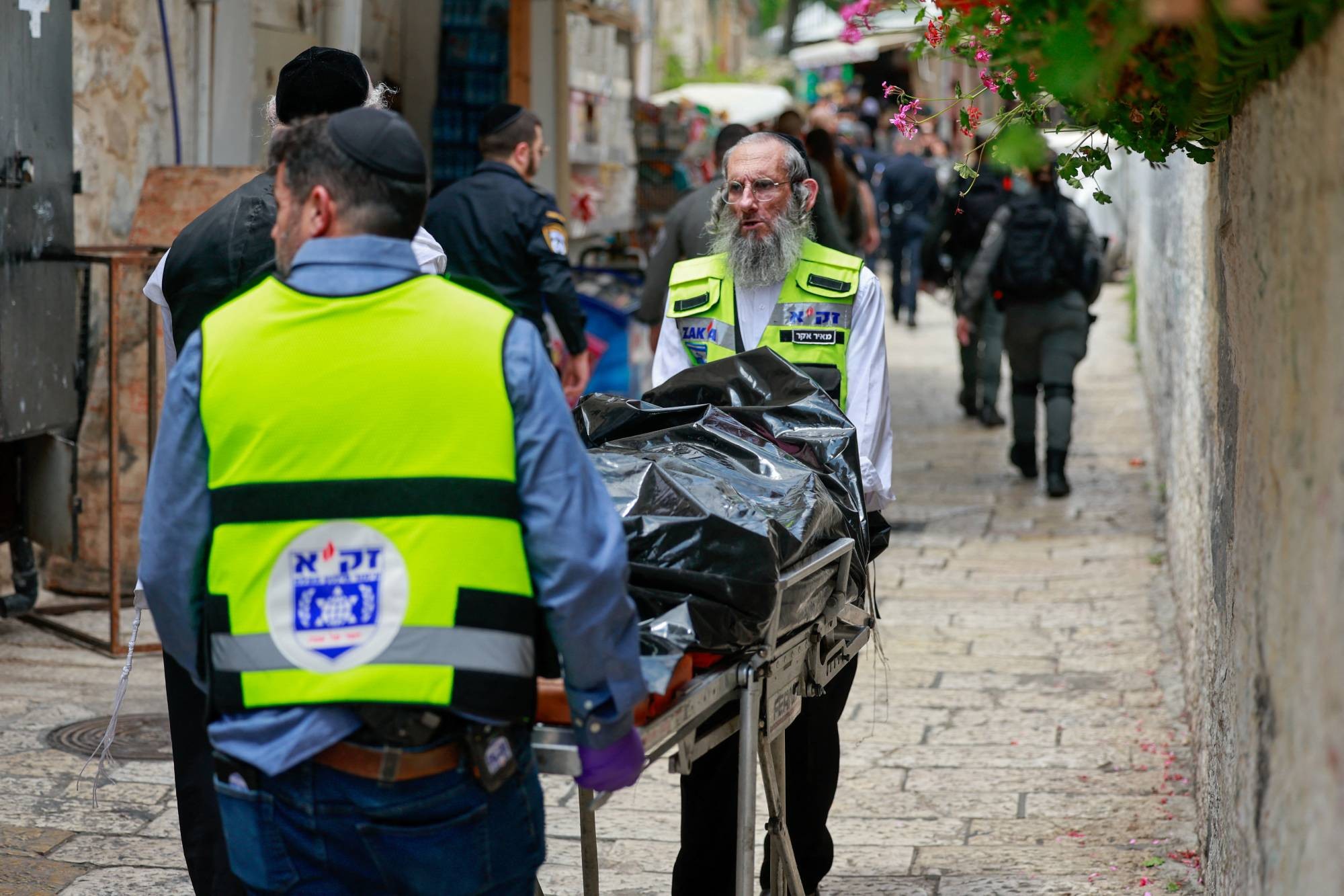 مسعفون إسرائيليون يحملون جثمان منفذ هجوم الطعن في القدس (رويترز).jpeg
