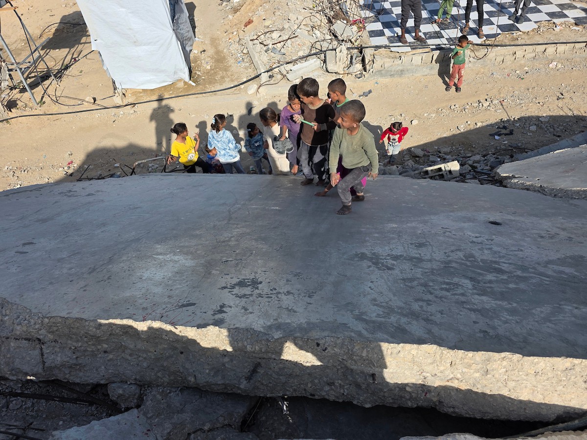 أطفال فلسطينيون يمشون على أسطح منازلهم المدمرة جراء الحرب الإسرائيلية في خان يونس (5).jpg