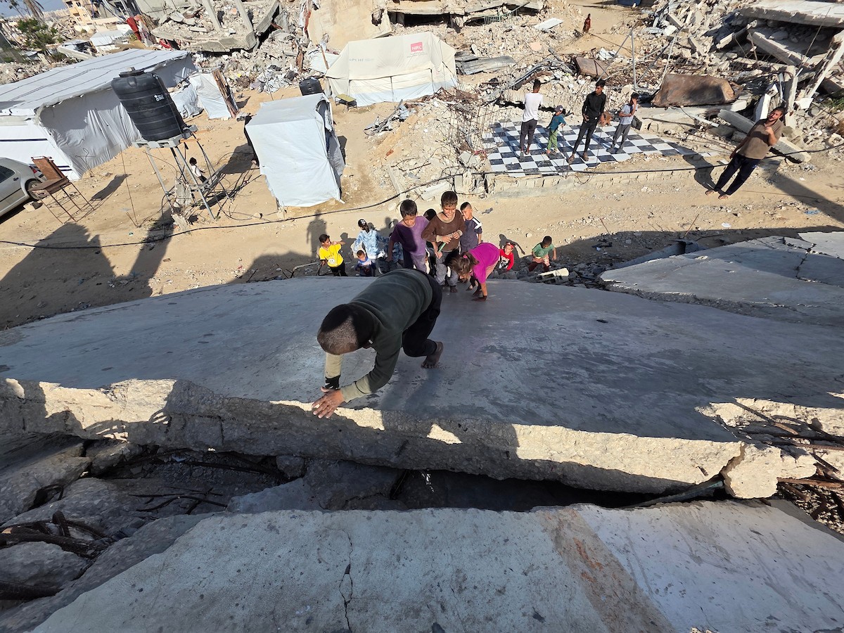 أطفال فلسطينيون يمشون على أسطح منازلهم المدمرة جراء الحرب الإسرائيلية في خان يونس (6).jpg