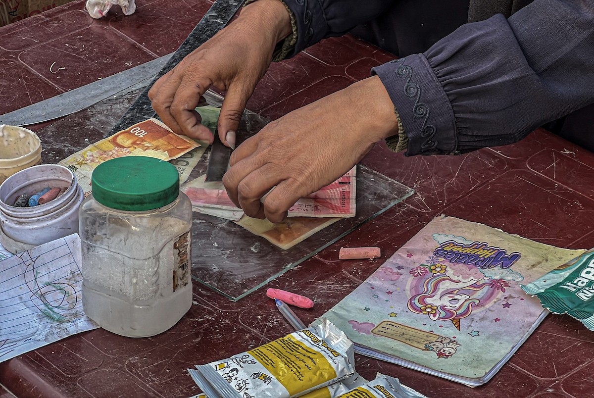الفلسطينية منال السعيداني تُصلح أوراقًا نقدية قديمة ومهترئة في ظل نفاد العملة الصعبة في قطاع غزة (12).jpg
