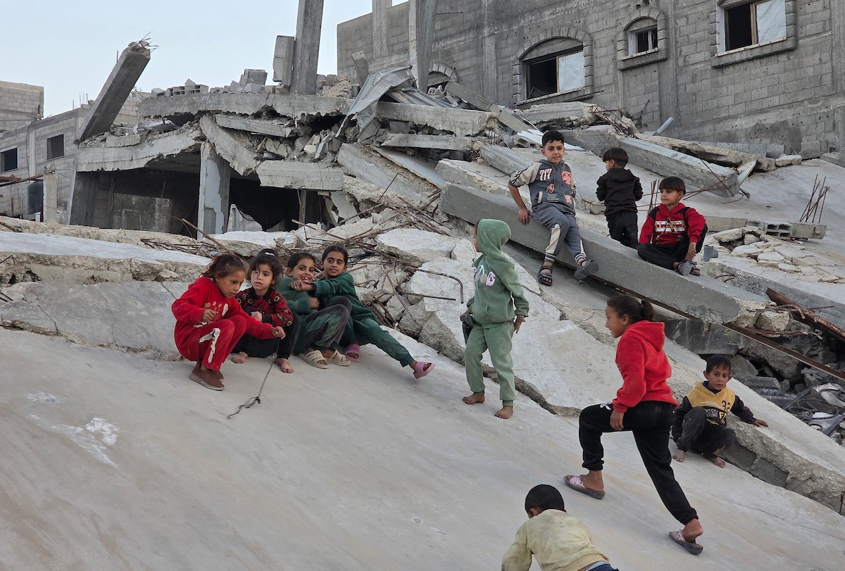 أطفال فلسطينيون يمشون على أسطح منازلهم المدمرة جراء الحرب الإسرائيلية في خان يونس (3).jpg