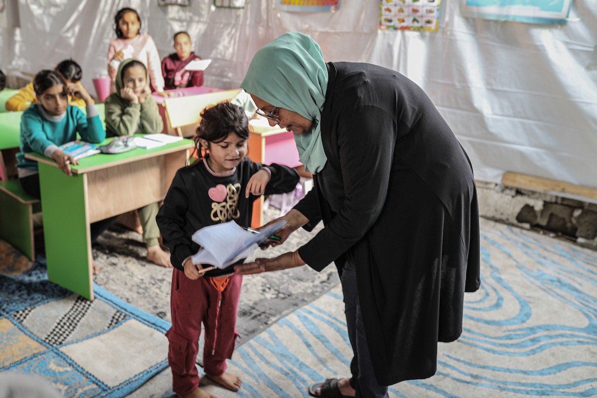 أطفال فلسطينيون نازحون يحضرون درسًا داخل خيمة تُستخدم كفصل دراسي مؤقت في ملجأ بدير البلح (9).jpg