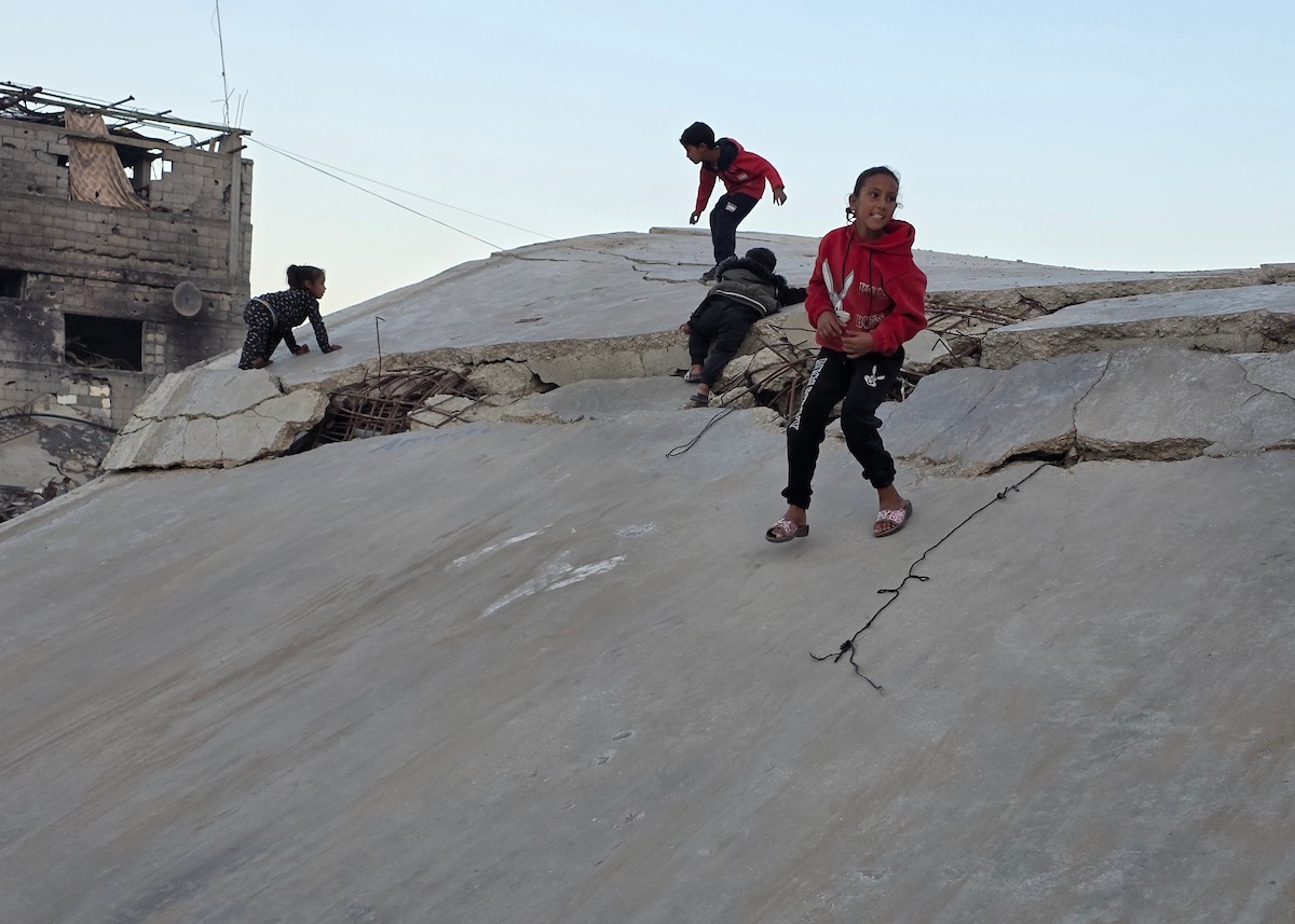 أطفال فلسطينيون يمشون على أسطح منازلهم المدمرة جراء الحرب الإسرائيلية في خان يونس (2).jpg